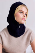 Woman wearing a dark blue knitted cowl against a light background
