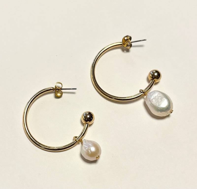 Gold hoop earrings with pearls on a light beige background