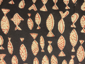 A close-up of a woven fabric with a repeating fish pattern. The fabric features cream-colored fish motifs outlined in red on a dark charcoal gray background.