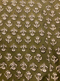 A close-up of a fabric or wallpaper pattern featuring a repeating block-printed floral motif in off-white on an olive green background.