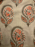 A close-up of a fabric or wallpaper pattern featuring dark brown paisley and floral motifs with orange and white accents on a warm beige background.