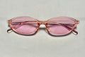 Pink sunglasses with a clear frame on a light gray background