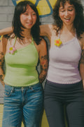 Two women wearing colorful tank tops with floral designs, standing against a wall.