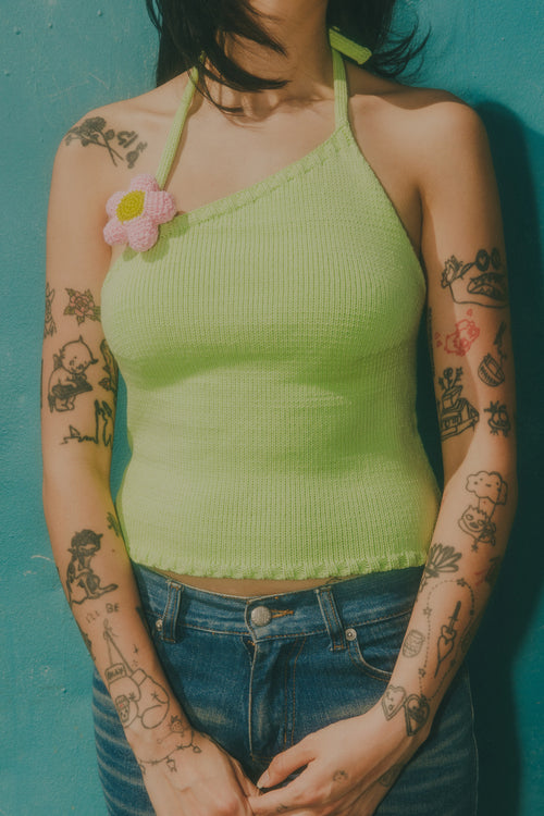 Person wearing a green ribbed tank top with floral design against a blue background