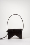 A black leather shoulder bag with a unique curved, wing-like silhouette and a single thin strap arching over a white studio background.
