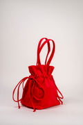 A bright red fabric drawstring pouch bag with two top handles, photographed on a clean light gray studio background.