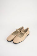 A pair of beige leather Mary Jane flats with square toes and small buckle straps, photographed on a clean white studio background.