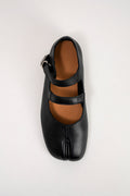 A single black leather Japanese tabi-style Mary Jane shoe with a silver buckle strap, photographed from a top-down view on a light gray background.