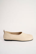 A single beige leather slip-on shoe with a black sole, shown in profile against a plain off-white background.
