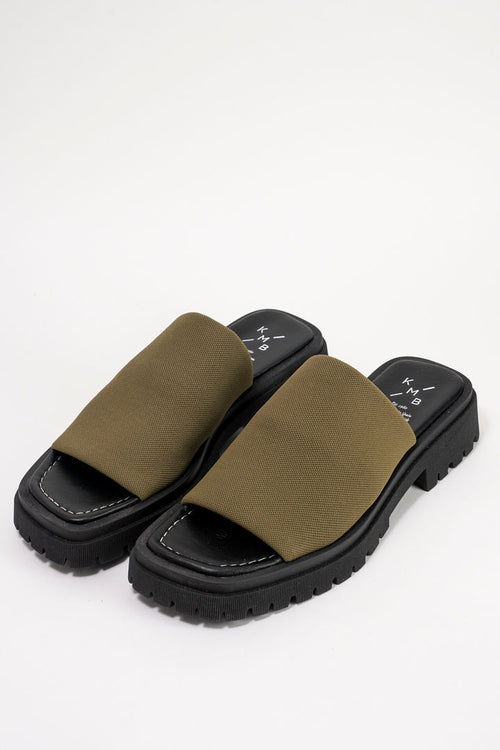 A pair of platform slide sandals with olive green fabric straps and chunky black soles, shown on a clean white background.