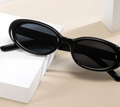 Black sunglasses on a beige surface with a white box in the background