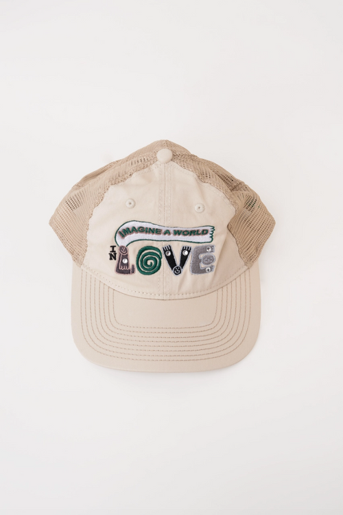 A beige trucker-style cap with a curved brim and beige mesh back, featuring a colorful embroidered graphic on the front that reads 'IMAGINING A WORLD OF LOVE' with a spiral heart design.