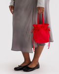 Person holding a red drawstring bag against a plain background