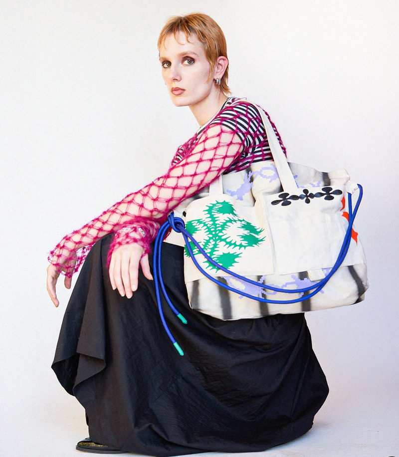 Person holding a large tote bag with colorful design on a white background