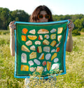 Person holding a green scarf with cheese pattern in a field