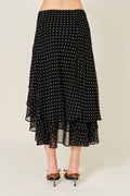 Black polka dot skirt worn by a person on a beige background