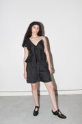Woman wearing a black ruffled top and shorts against a white background