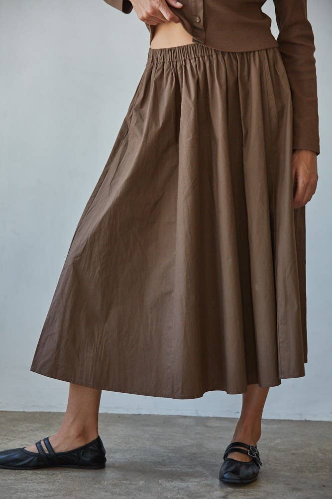 Person wearing a brown skirt with a plain background