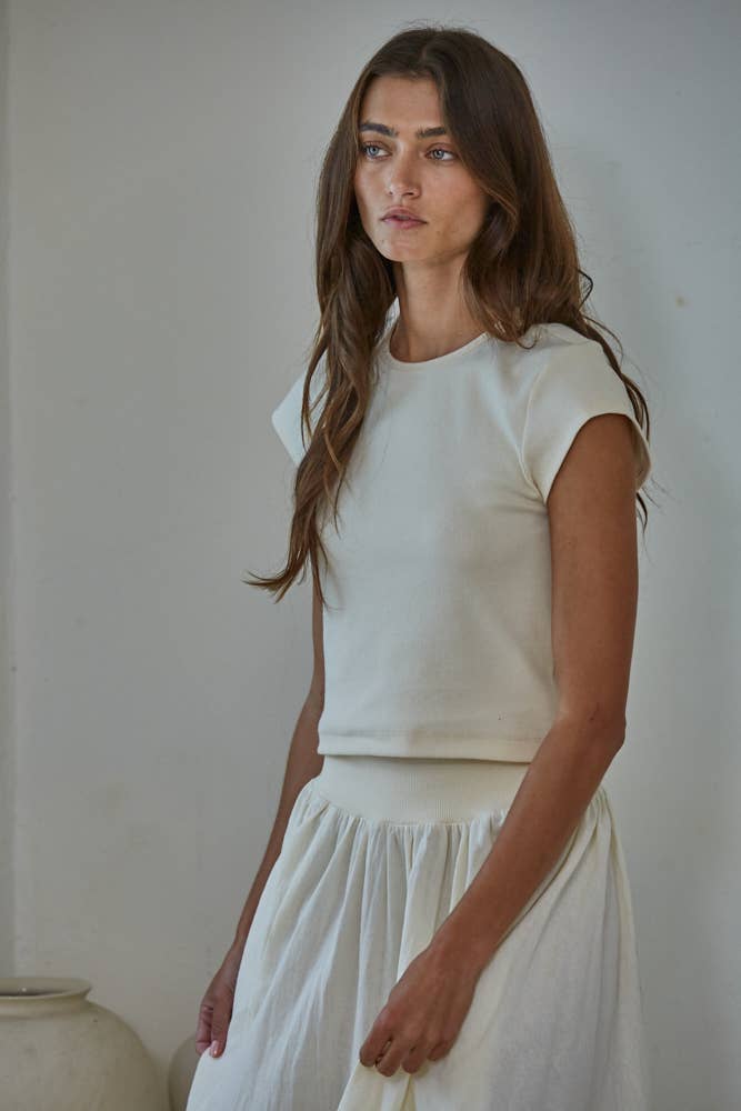 Woman wearing a white top and skirt against a plain background