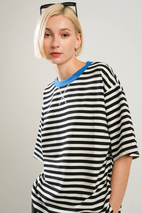 Person wearing a black and white striped shirt with a blue collar against a plain background