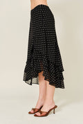 Black polka dot skirt worn by a person on a beige background