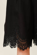 Black lace-trimmed dress on a beige background