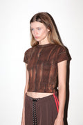 Model wearing a brown textured top and pants with red accents on a white background
