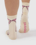 Beige socks with pink bows and 'BAGGU' branding on a white background