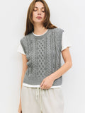 Woman wearing a gray sleeveless knitted top against a white background