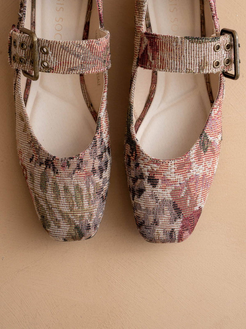 Pair of floral-patterned shoes with buckles on a beige background
