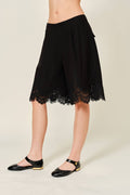 Black lace skirt worn by a person on a plain background