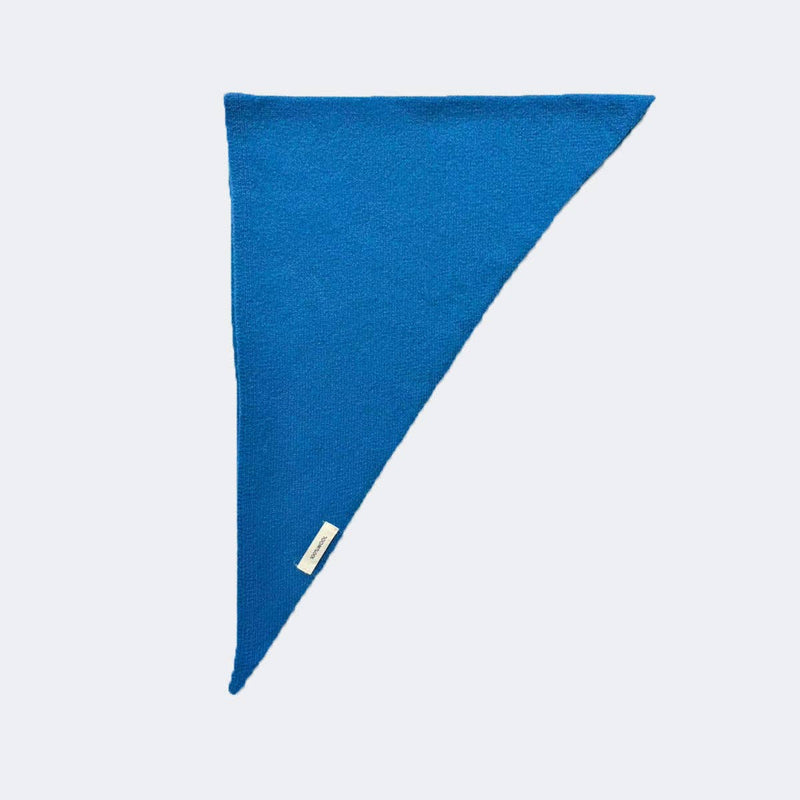 Blue triangular pillow with a brand label on a light gray background
