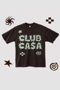 A dark brown short-sleeve t-shirt with a light green abstract graphic print on the front, displayed against a light gray background with decorative brown doodle elements in the corners.
