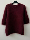 Maroon sweater on a hanger against a white background