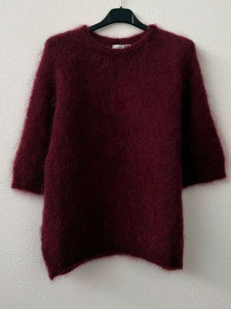 Maroon sweater on a hanger against a white background