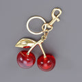 Keychain with red cherry-like beads and gold accents on a gray background