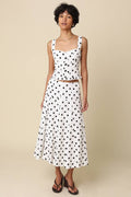 Woman wearing a polka dot dress against a beige background