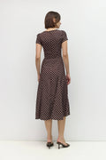 Woman wearing a brown polka dot dress against a white background