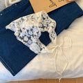 White lace bralette with blue jeans on a wooden surface