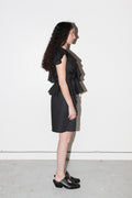 Woman wearing a black ruffled dress against a white background