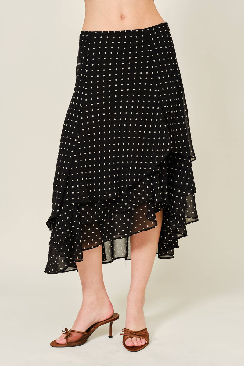 Black polka dot skirt worn by a person on a beige background