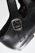 Black leather shoe with a silver buckle on a white background