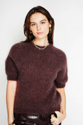 Woman wearing a dark brown sweater against a white background