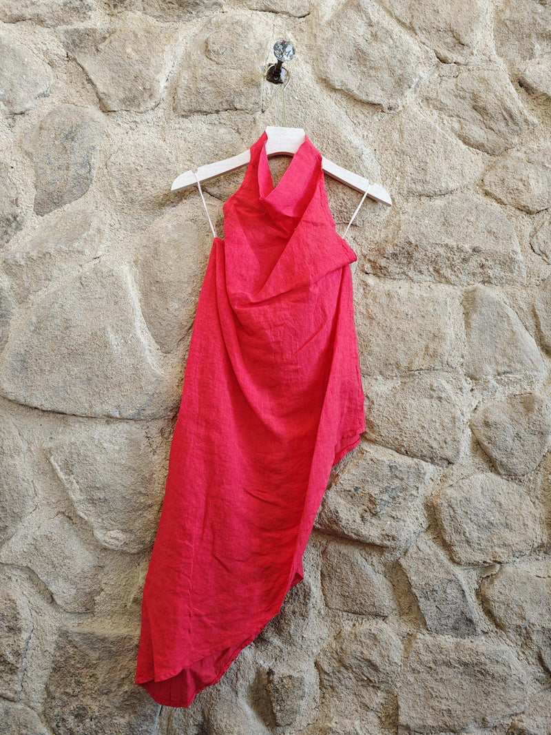 Red halter dress on a hanger against a stone wall