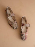 Pair of floral-patterned shoes with buckles on a beige background