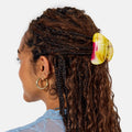 Person with braided hair featuring a yellow hair clip on a white background
