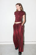 Model wearing a burgundy outfit with a top and wide-leg pants against a white background