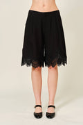 Black lace shorts worn by a person on a plain background