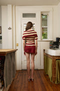 Woman in a striped sweater and red skirt standing in a kitchen.