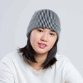 Woman wearing a black and white striped beanie against a plain background